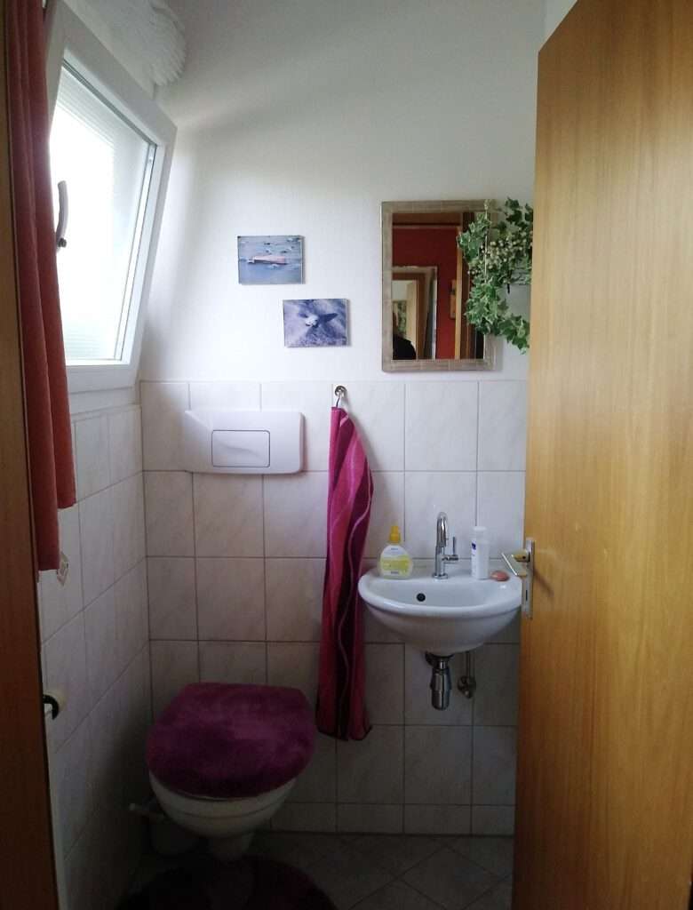 Badezimmer mit alten Fliesen an der Wand und auf dem Boden.